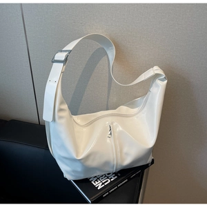 Détail d'un sac d'épaule en cuir verni blanc avec large bandoulière et boucle en métal argent