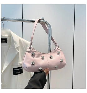 Détail du sac à épaule en cuir rose avec clous métalliques argentés et bandoulière