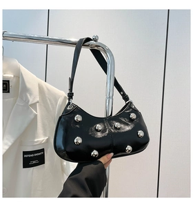 Détail du sac à bandoulière noir brillant avec rivets argentés au style punk moderne