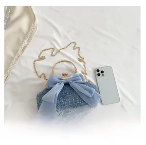 Blue tweed evening bag with chiffon bow and gold clasp next to a phone for size