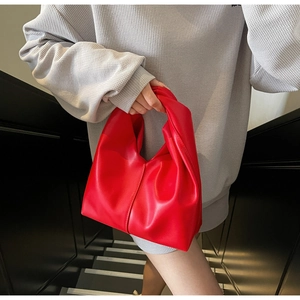 Detail of red vegan leather hobo bag with knotted handle and pleated triangle design