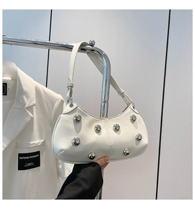 Détail du sac demi-lune blanc avec rivets argentés et texture en cuir mat