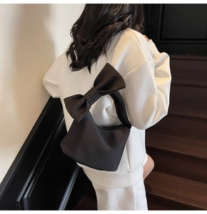 Detail of black nylon shoulder bag featuring large bow decor and silver chain strap
