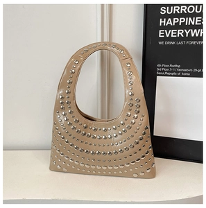 Close-up of silver stud rivets in curved layers on beige patent leather shoulder bag