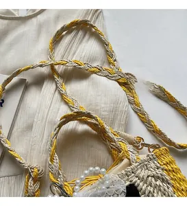 Detail showing a braided long shoulder strap and pearl handle with lace on a straw bag