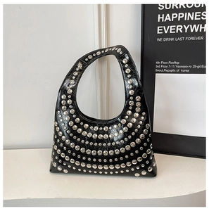 Close-up of shiny black leather surface with decorative silver metal rivets on bag