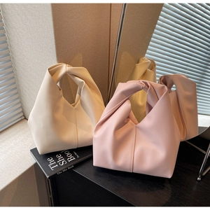 Detail of elegant handbags in cream and pink PU leather with stylish knotted handles
