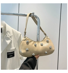 Détail du sac beige avec de grandes sphères en métal argenté sur similicuir brillant