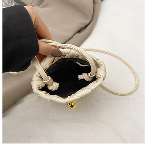 Detail view of woven leather bag with drawstring closure and golden metal bead accent