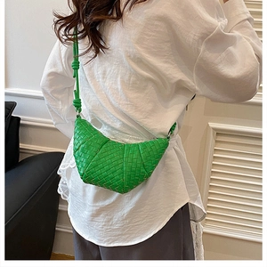 Detail of green handmade woven crescent crossbody bag with Intrecciato leather texture