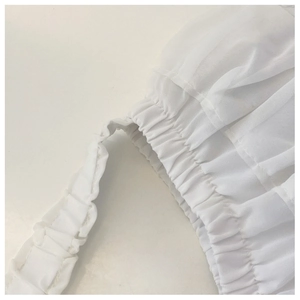 Detailed shot of white pleated chiffon fabric with ruffled texture and elastic smocking
