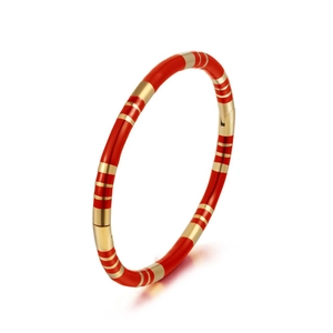 Close-up of a gold-toned bangle with red enamel finish and striped texture detail