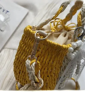 Close-up of woven straw bag with pearl handle, gold hardware and lace detail