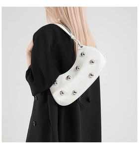 Gros plan du sac en croissant blanc avec rivets argentés sur un tailleur noir