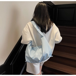 Mannequin portant un grand sac hobo en cuir verni bleu clair sur un escalier en bois
