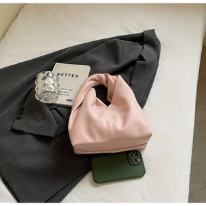 Detail of pink cloud bag with knotted handle and vertical stitching on grey blazer