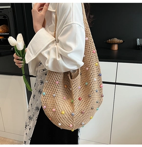 Detail of hand-woven hollow straw tote bag featuring colorful bead accents and pearl decor