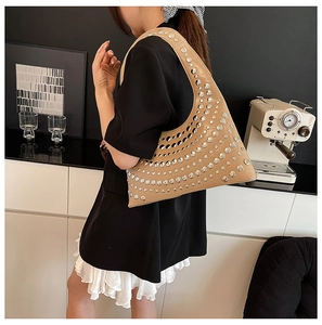Detail of khaki leather shoulder bag with silver studs on a model in a modern room