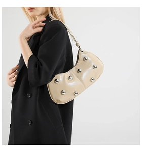 Détail d'un sac à bandoulière chic crème en cuir brillant avec des rivets métalliques