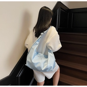 Gros plan du sac en croissant bleu clair brillant avec large bandoulière en situation