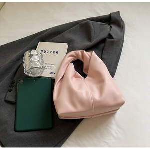 Detail of a light pink handbag with ruched handle and soft PU leather on office props