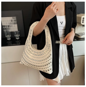 Detail of cream hobo bag with silver rivets worn by a model in a modern setting