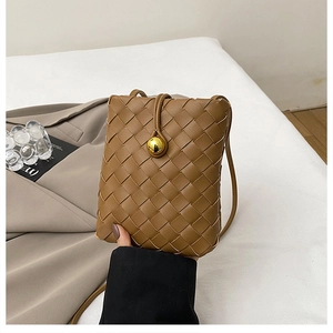 Detail of woven leather mini crossbody bag featuring a golden buckle and magnetic closure