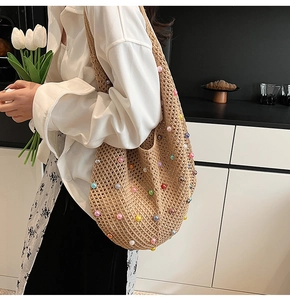 Detail of bohemian woven tote bag featuring colorful faux pearls on natural straw fiber