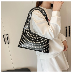 Detailed close-up of silver studs on black faux leather shoulder bag with glossy finish