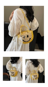 Detail of straw woven bag featuring smiley face and pearl flower decorations with lace bow
