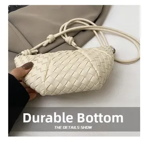Detail showing the wear-resistant bottom of this woven cream-colored crossbody bag