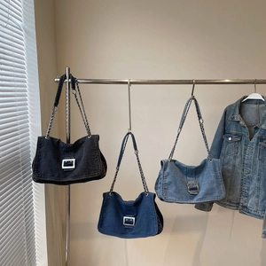Three-color denim chain tote bags in black and blue hanging on a metal rack