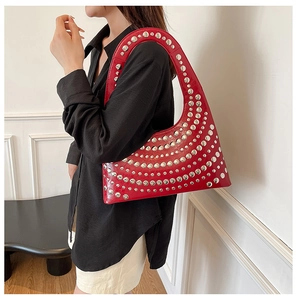 Detail of red punk hobo bag with silver studs and glossy patent finish on leather
