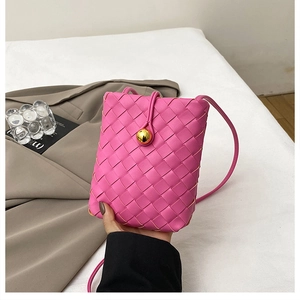 Close-up of pink woven leather phone bag with a gold spherical clasp and cross-weave texture
