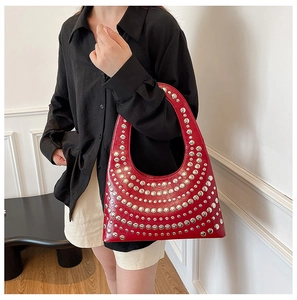 Detail of red studded hobo bag with silver rivets carried by a model in black shirt