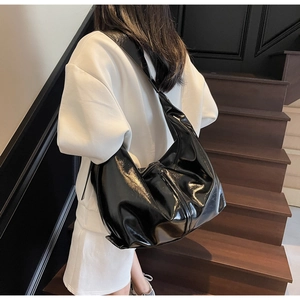 Détail du sac hobo noir brillant à large bandoulière dans un style urbain très moderne