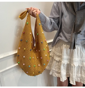 Detail of yellow crochet hobo bag with colorful pearl embellishments and knit texture