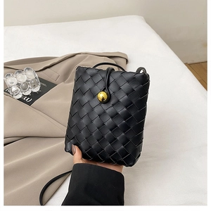 Detailed view of black woven crossbody phone bag with luxury gold ball clasp and leather strap