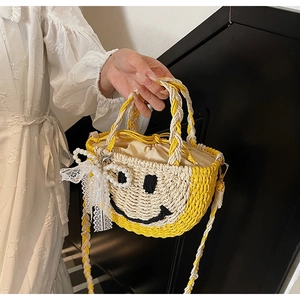 Close-up of woven straw bag featuring smiley face pattern and lace bow detail