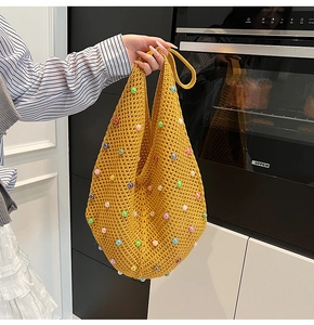 Detail of yellow crochet knit bag featuring colorful pearl beads and hollow mesh pattern