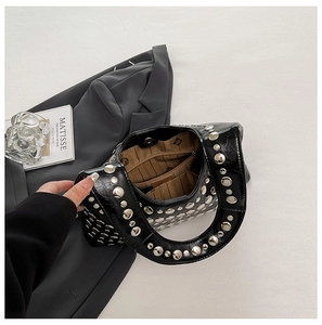Detail of silver rivets on black leather handbag with a high-fashion punk aesthetic