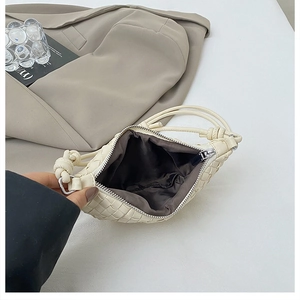 Close-up of cream hand-woven dumpling bag with signature leather knots and silver zipper
