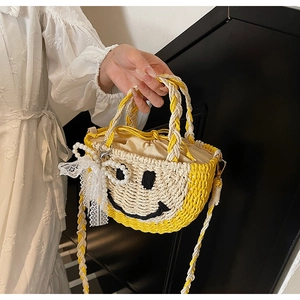 Detail of hand-woven straw bag with cute smiley face, lace bow and pearl pendant