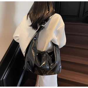 Détail du sac à bandoulière en cuir verni noir avec boucle de réglage argentée