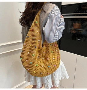Detail of a ginger yellow hand-knit crochet shoulder bag with colorful pearl beads