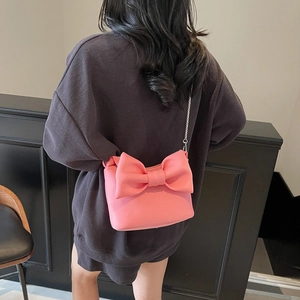 Pink nylon pillow bag with bow and silver chain strap worn by a model in interior