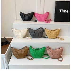 Detailed view of multiple colors of woven croissant crescent bags on a display stand