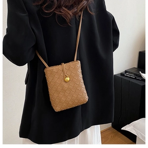 Detail of light brown woven leather phone bag featuring a signature gold sphere buckle