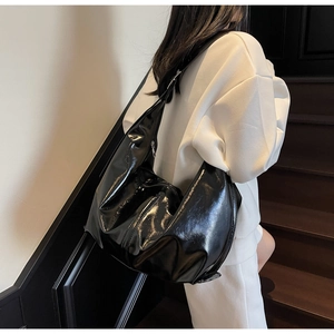 Détail du sac hobo en cuir verni noir brillant avec un design minimaliste spacieux