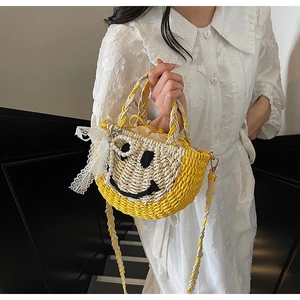 Close-up of semi-circle straw bag with smiling face, lace bow, and pearl pendant detail